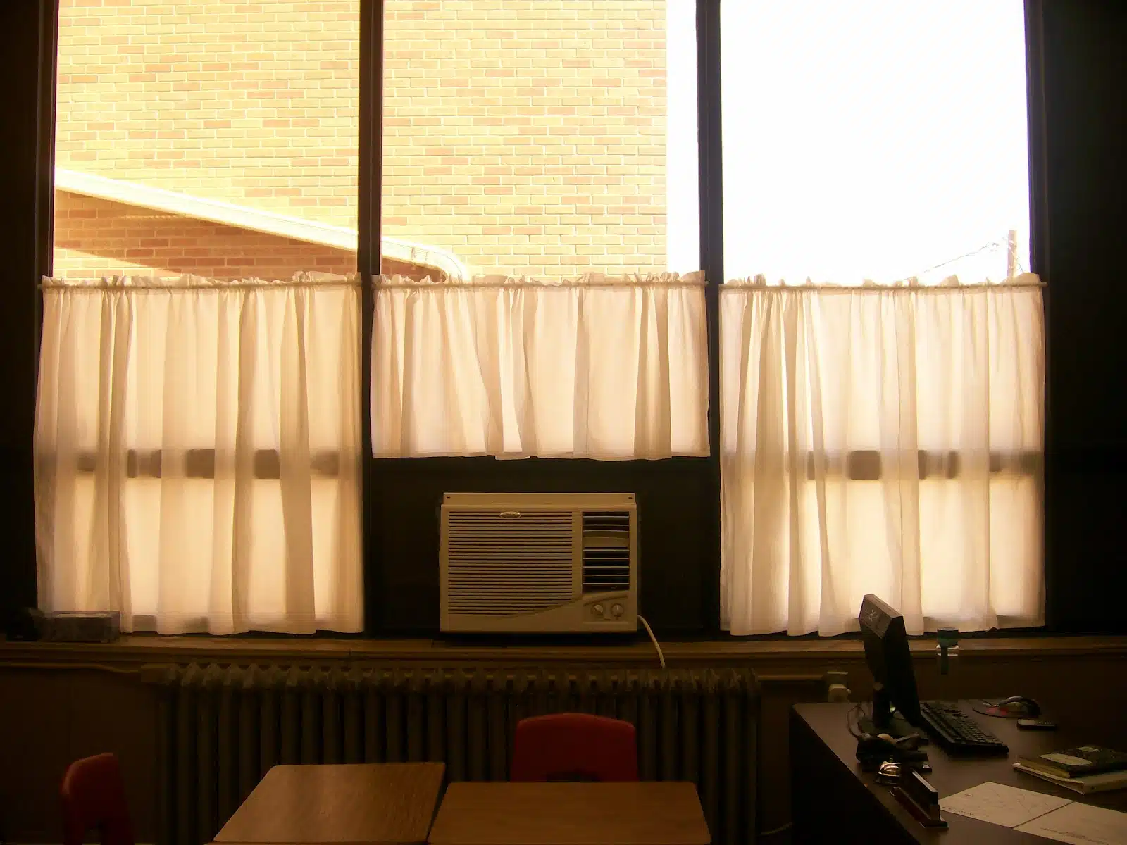 wall of windows in classroom with white curtains. 