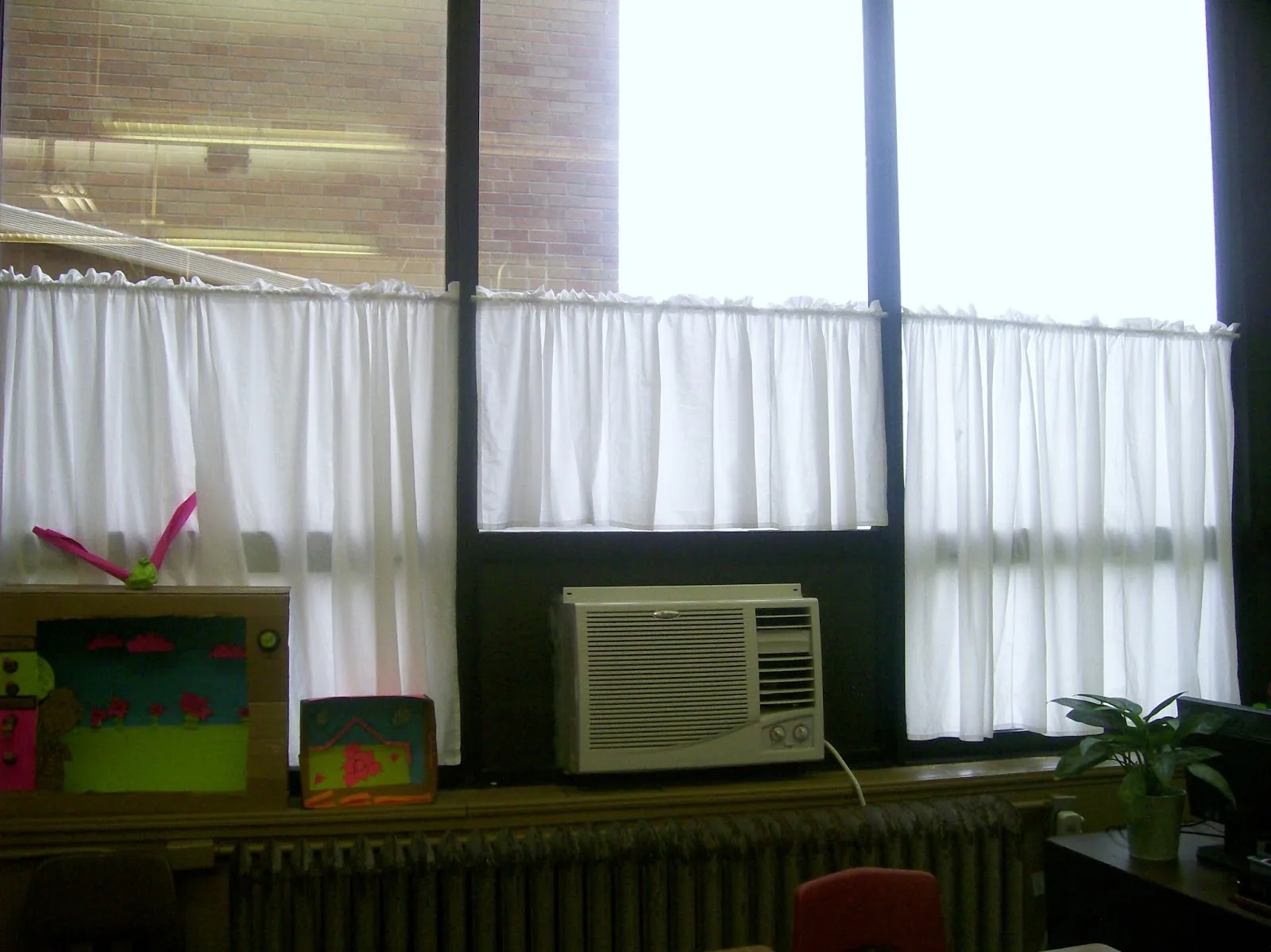 wall of windows in classroom with white curtains. 