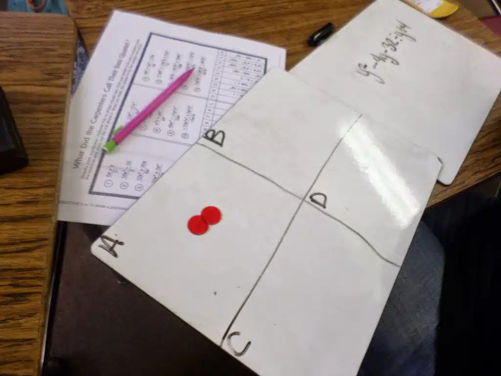 dry erase board with two chips on "A" in place your bets review game. 