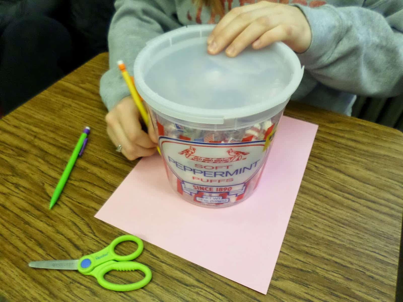 student tracing circular container for Cutting Pi Discovery Activity.  