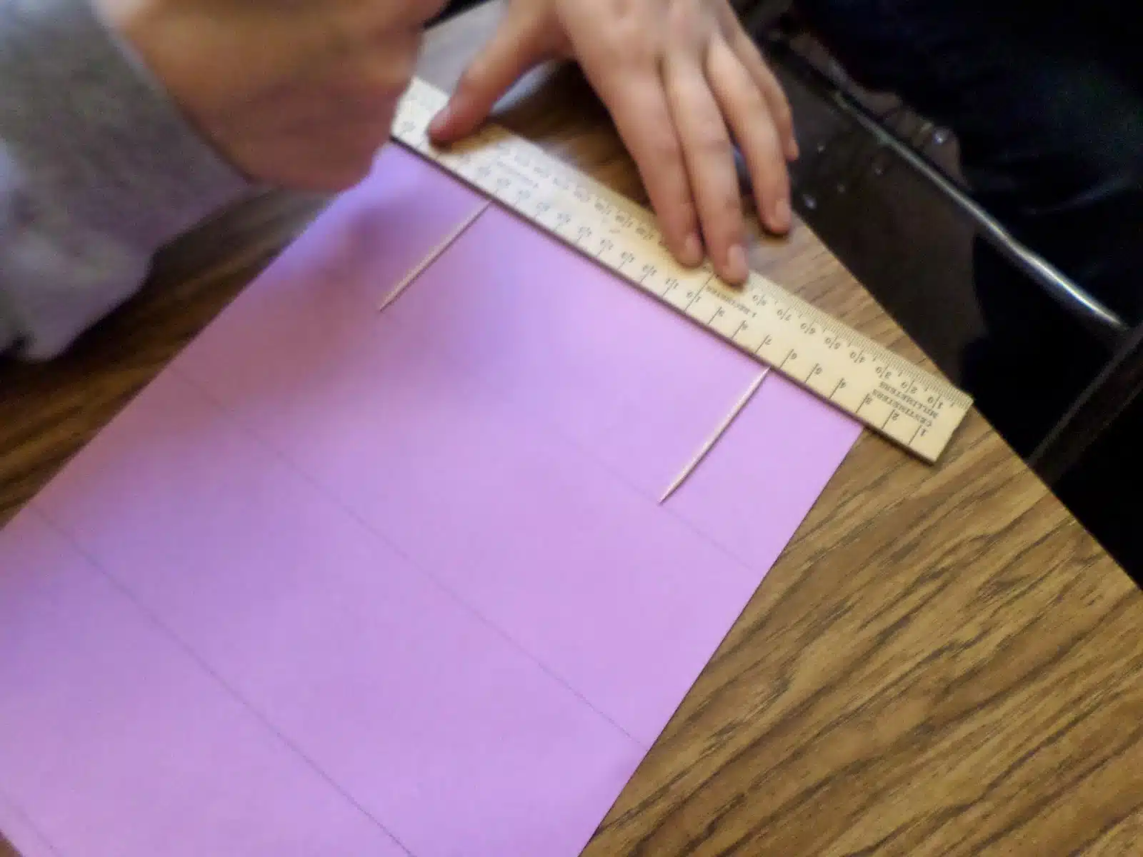 student using ruler to draw lines the width of a tooth pick apart. 