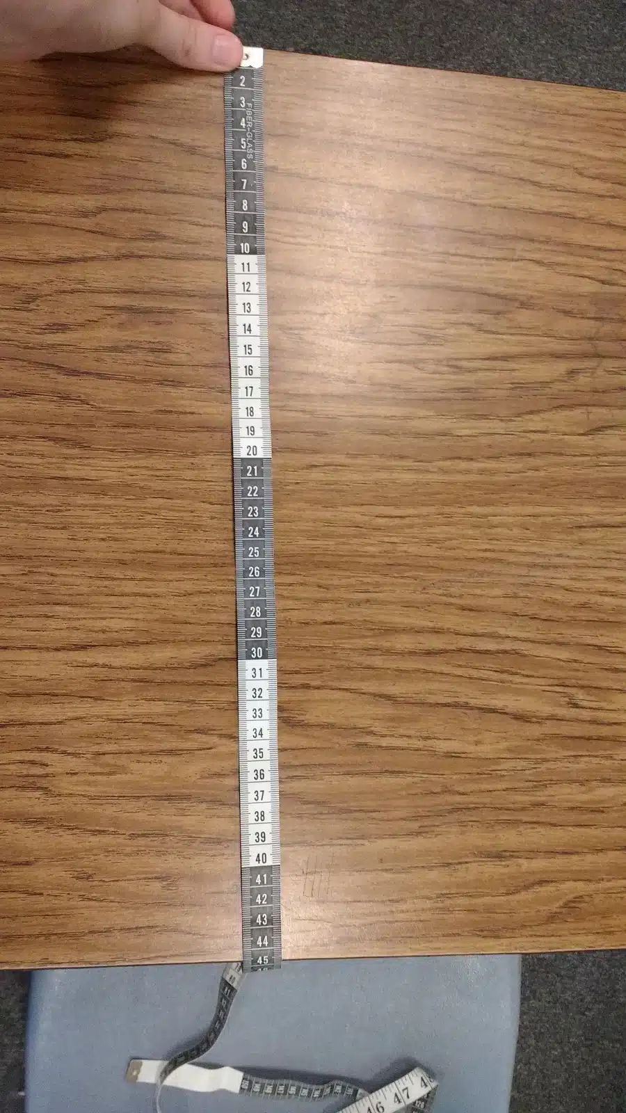 student measuring desk with tape measure. 