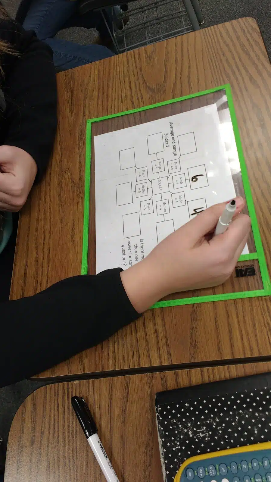 student working on mean, median, mode, and range spider puzzles