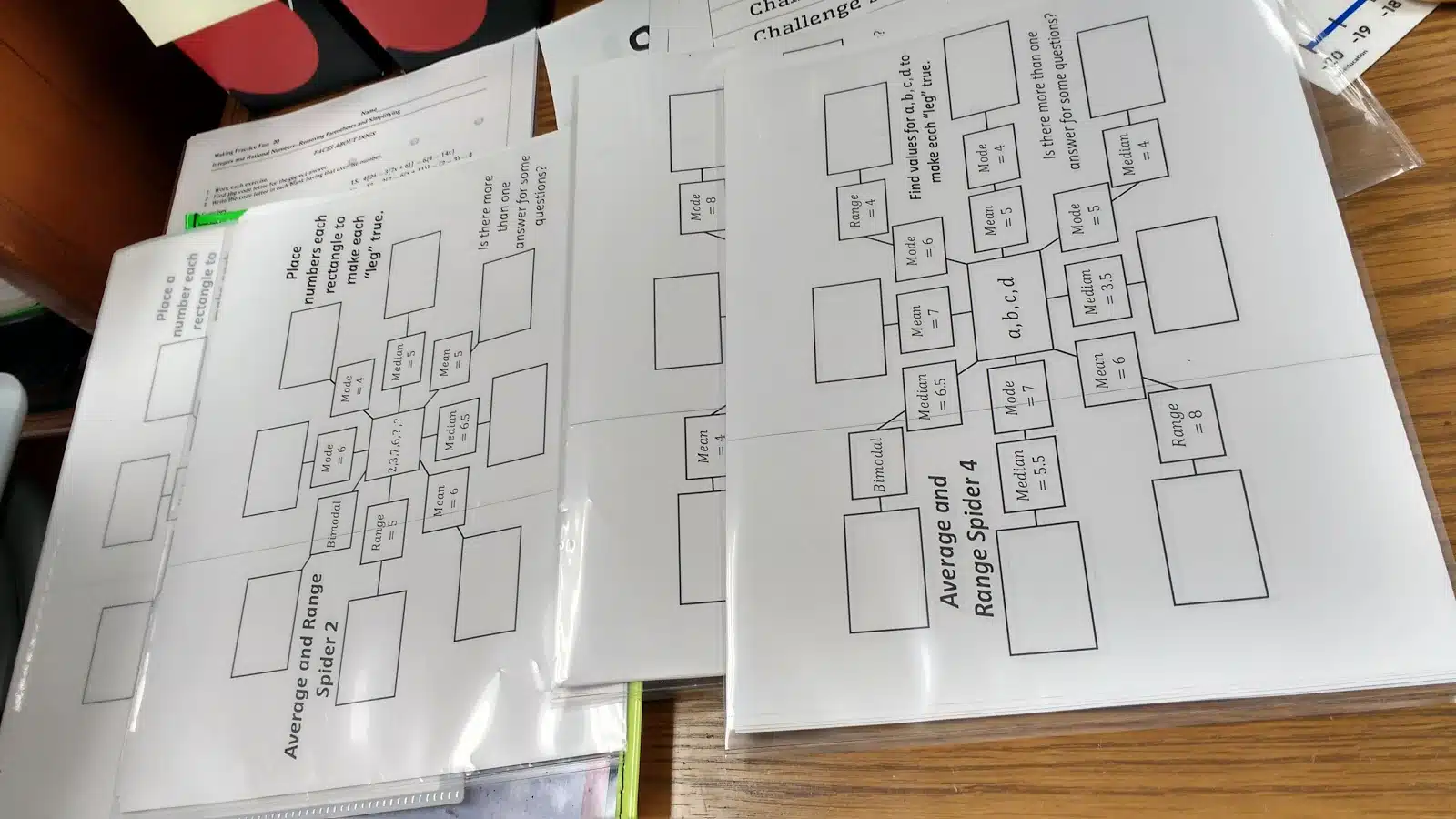 different levels of mean, median, mode, and range spider puzzles laying on teacher desk. 