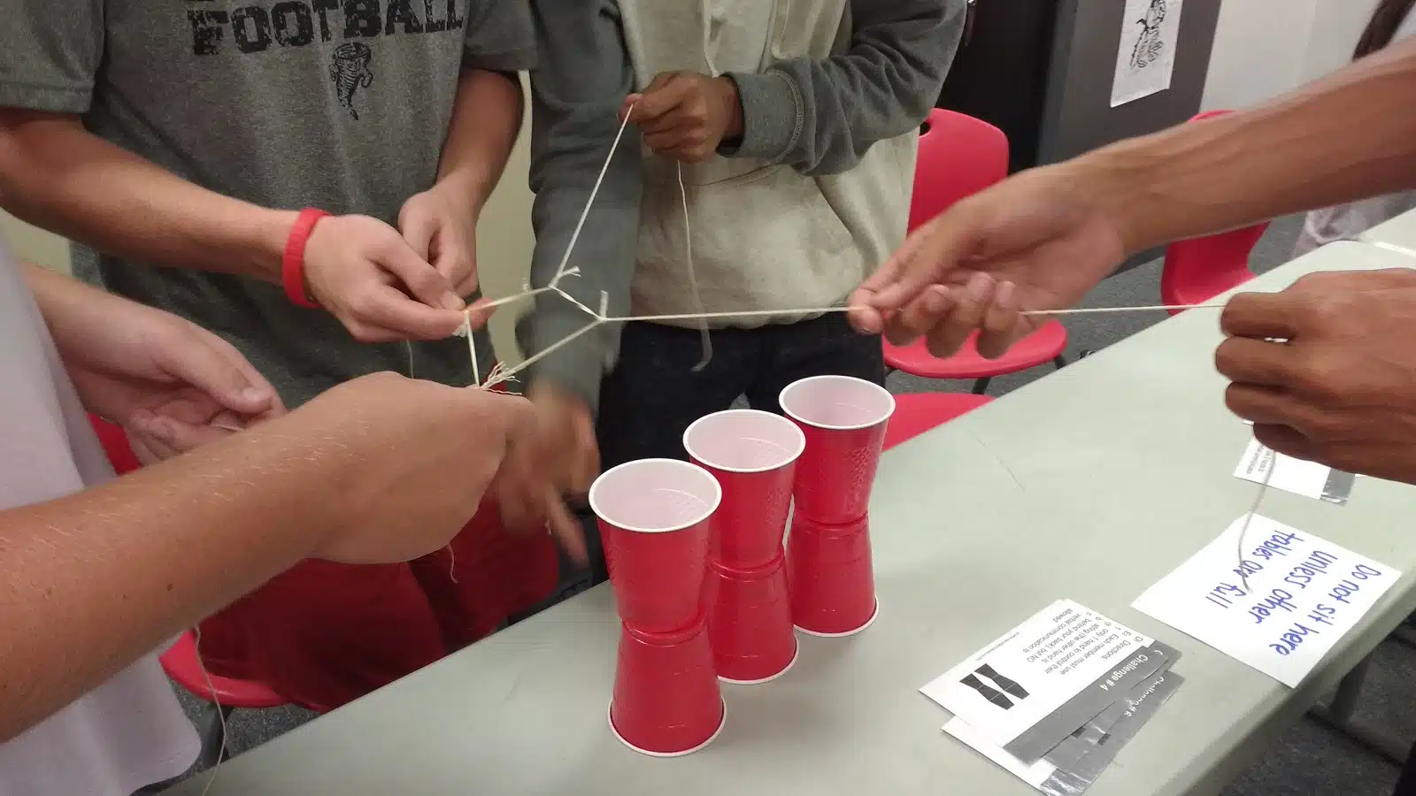 high school students participating in cup stacking challenge as a team building activity during the first week of school 