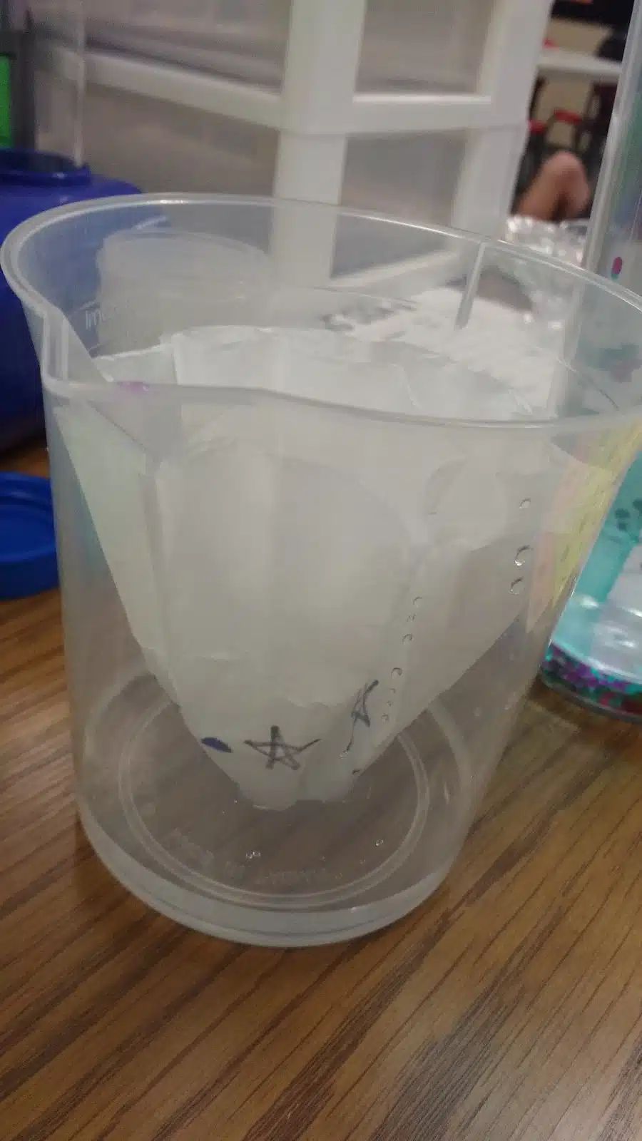 coffee filter in plastic beaker with water in bottom. 