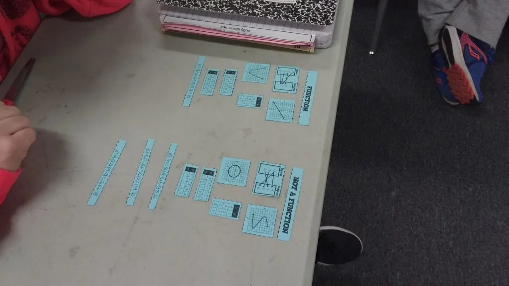 function vs not a function card sort spread out on desk in high school math classroom. 