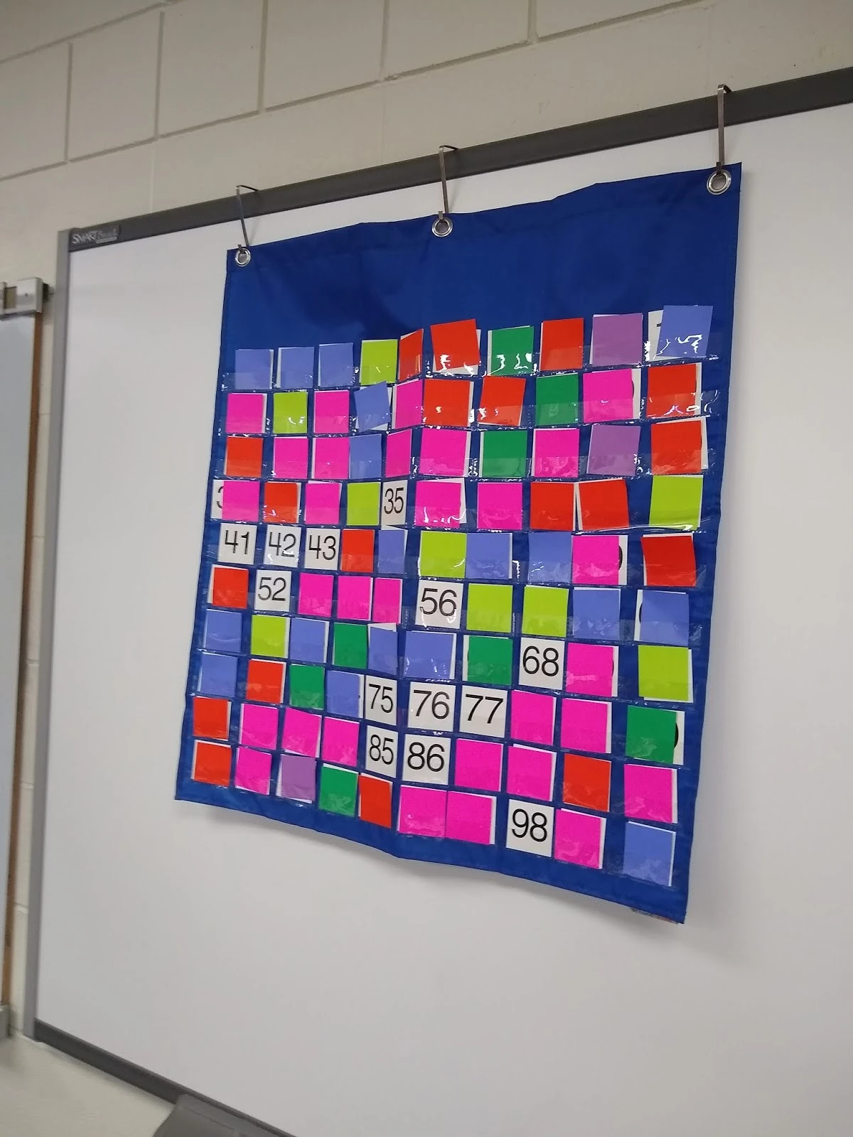 hundred chart with some numbers covered with squares of colored paper for yearly number challenge. 