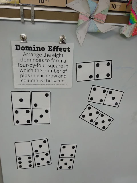 domino effect puzzle hanging on dry erase board. 