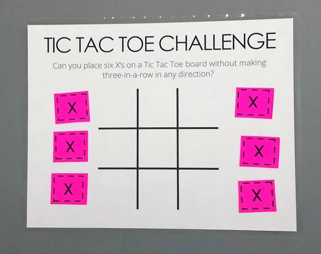 Tic Tac Toe Challenge Puzzle on laminated paper with six pink X's. 