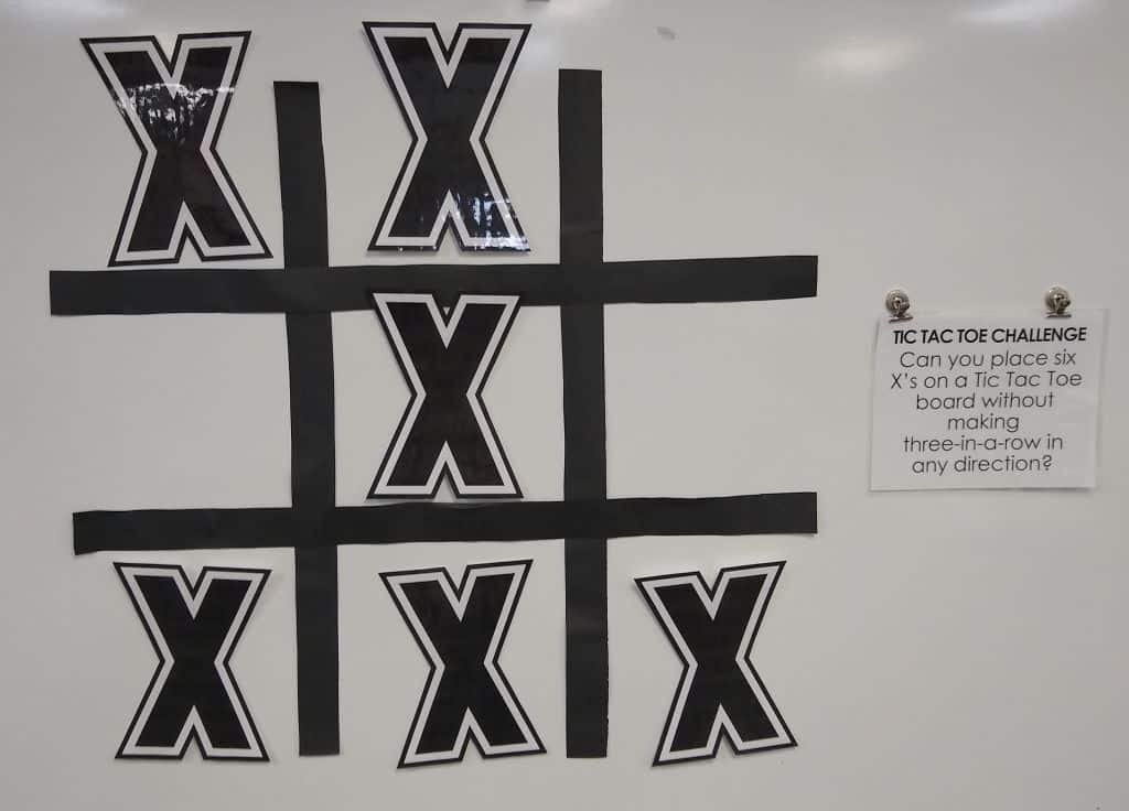 jumbo version of tic tac toe puzzle hanging on dry erase board with magnets 