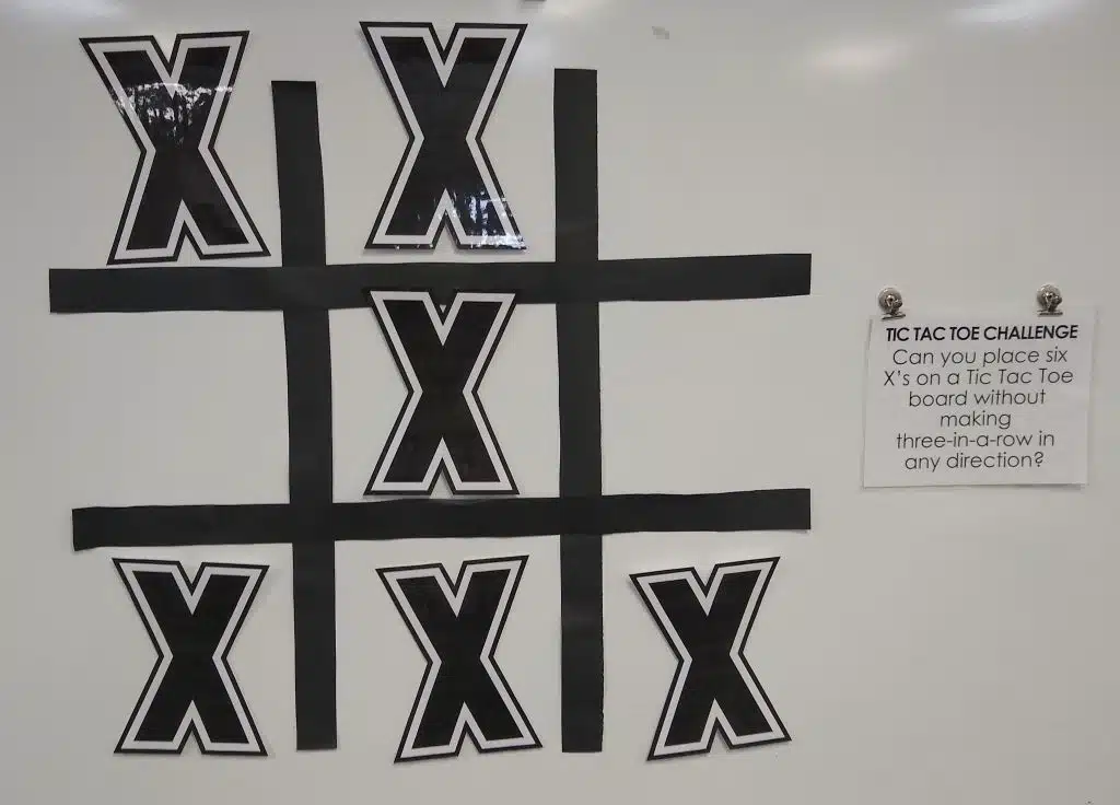 jumbo version of tic tac toe puzzle hanging on dry erase board with magnets 