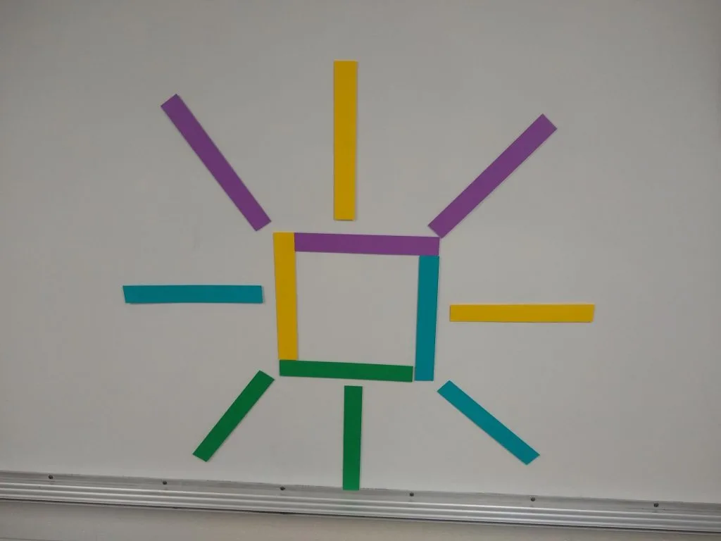 paper strips on dry erase board to illustrate let's make squares activity. 
