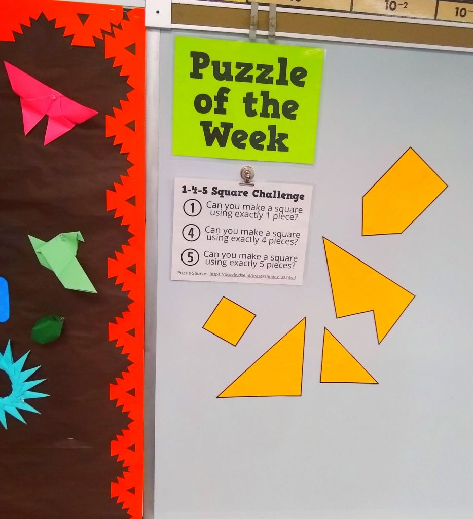 5 Piece Square Puzzle hanging on dry erase board in high school math classroom under sign which reads "Puzzle of the Week" 