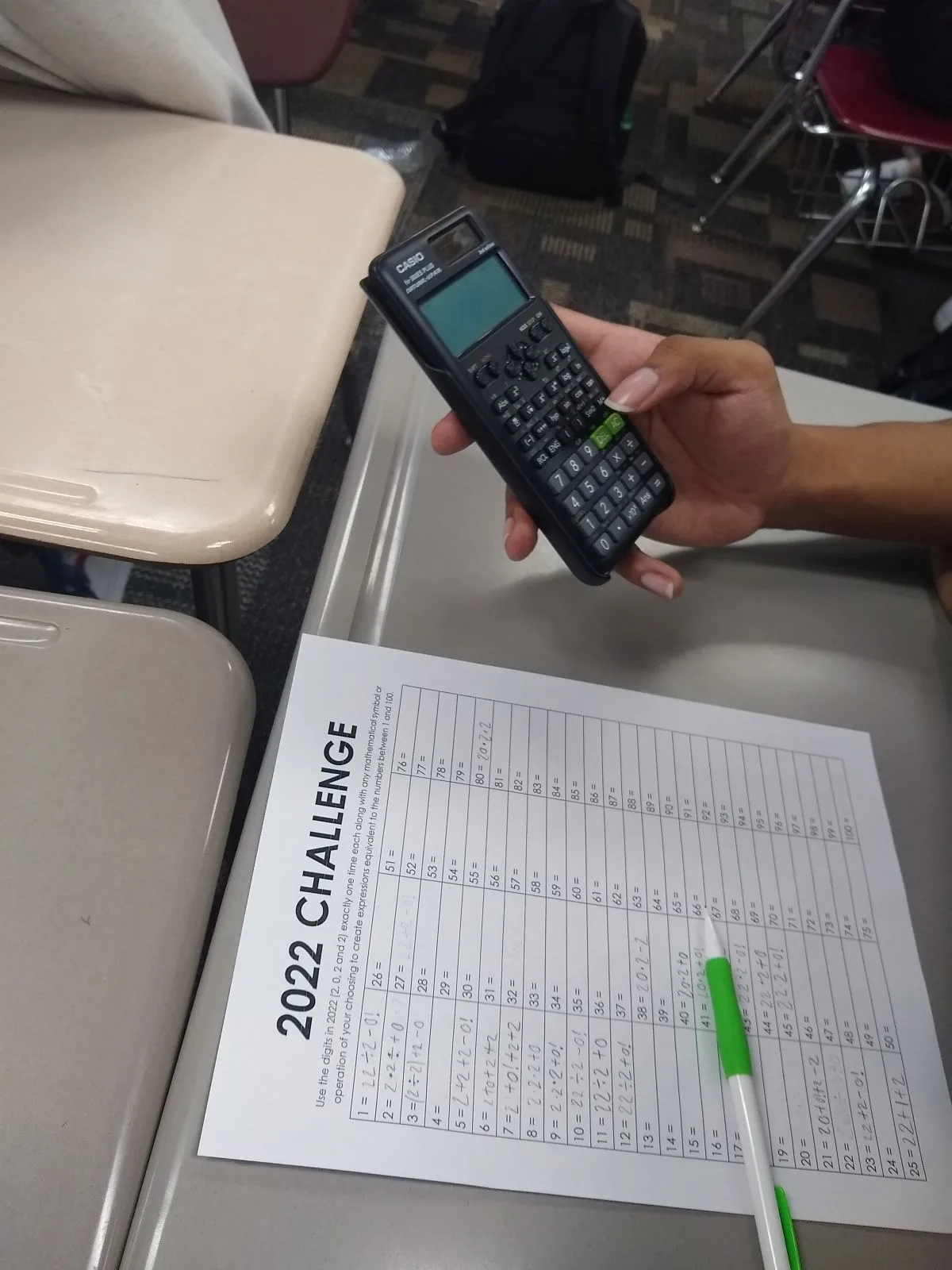 Student hand holding calculator while working on 2022 Challenge 