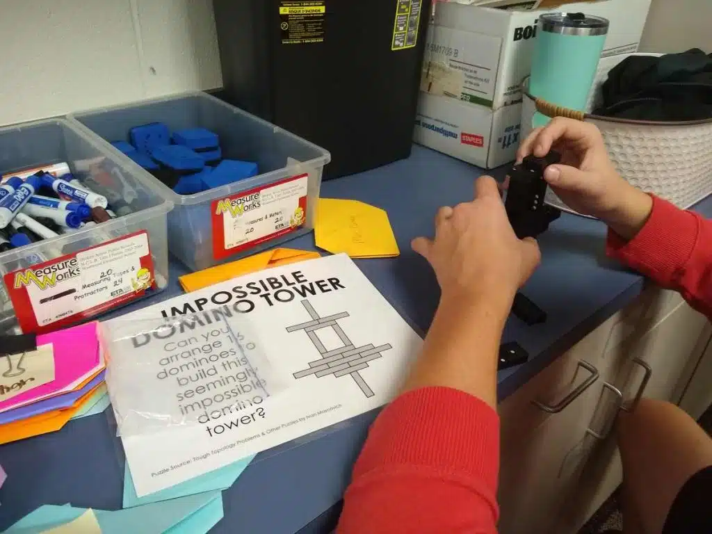 Student attempting to solve impossible domino tower puzzle. 