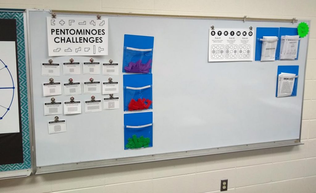 dry erase board in high school math classroom featuring puzzles for students to solve 