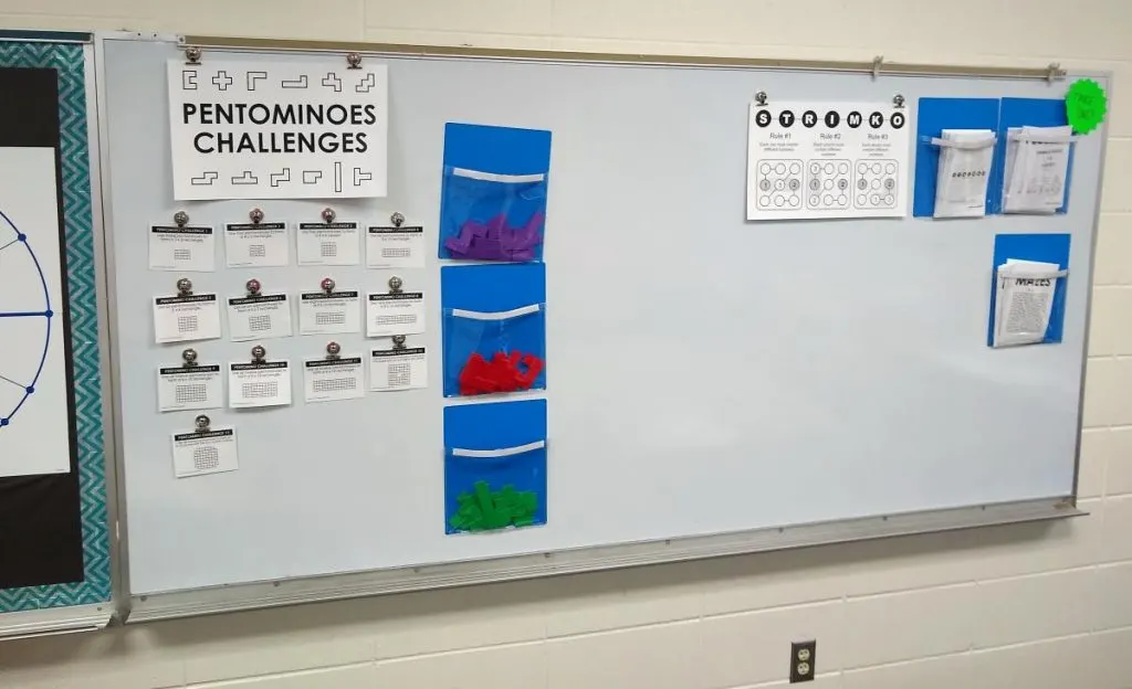 dry erase board in high school math classroom featuring puzzles for students to solve 