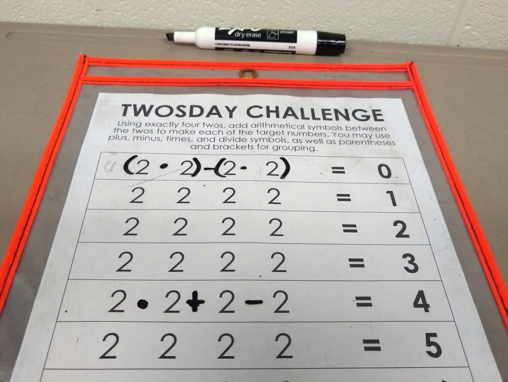 Dry Erase Pocket with Twosday Challenge placed inside. Several example problems solved. 