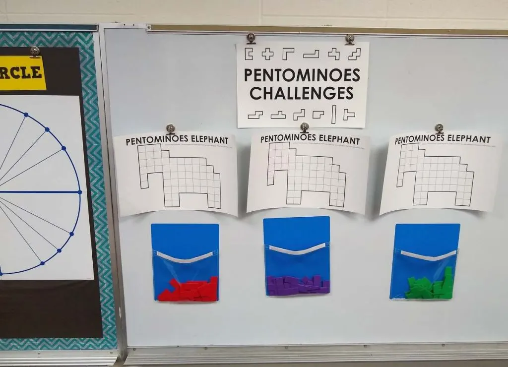three copies of elephant pentominoes puzzle hanging on dry erase board. 