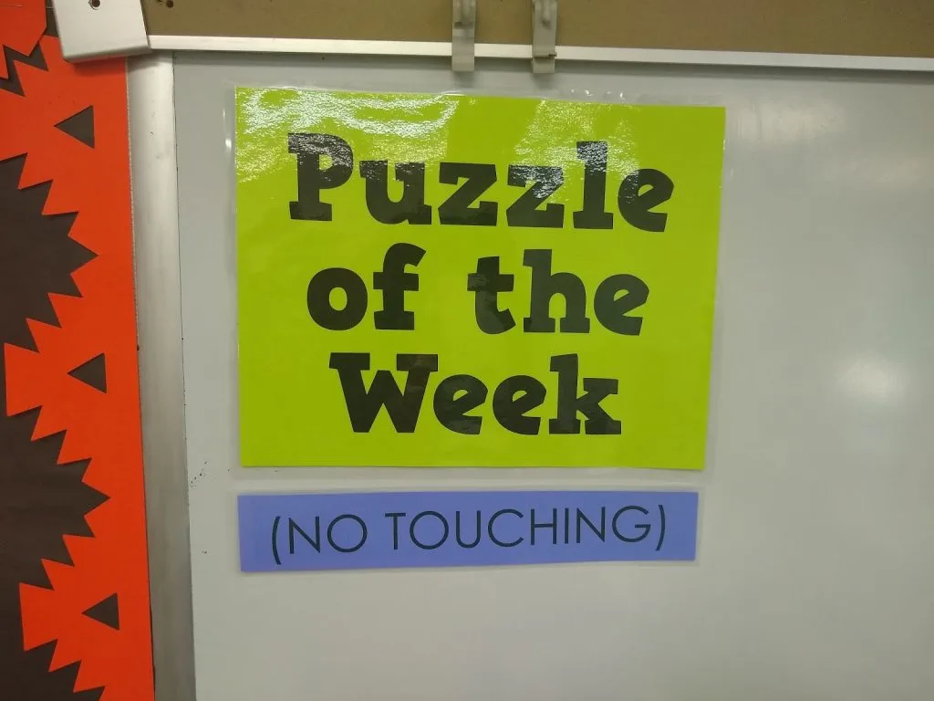 Puzzle of the Week Poster with "No Touching" Poster Below. 
