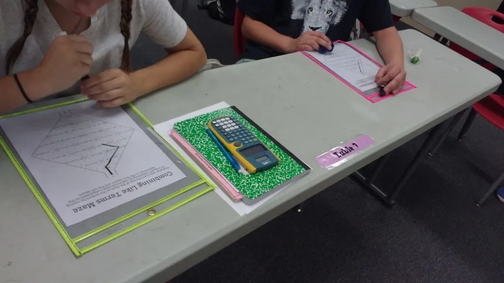 Students working on combining like terms puzzle in dry erase pockets in high school math classroom 