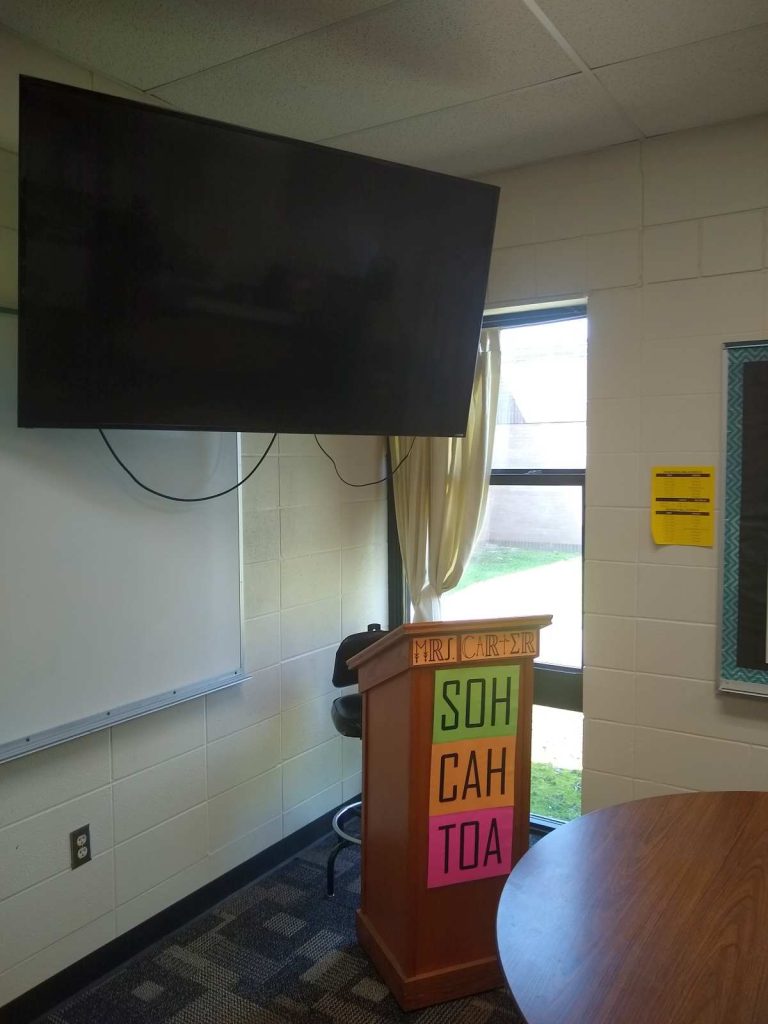 flat screen television hanging above podium in high school math classroom 
