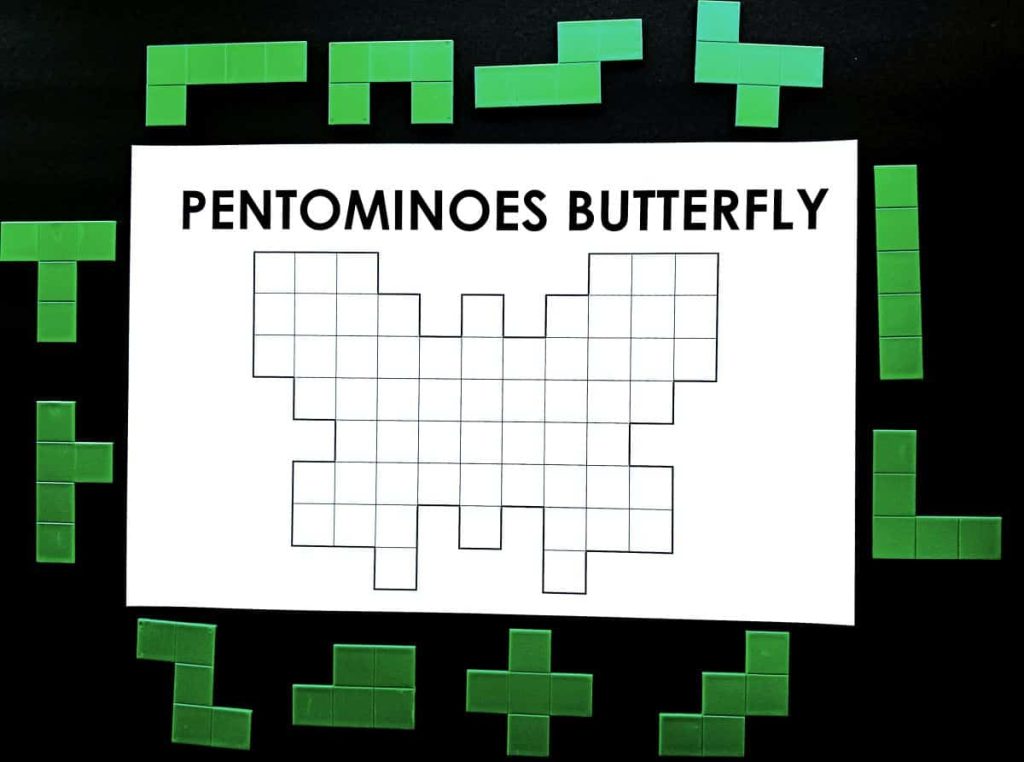puzzle kupu-kupu pentomino dicetak di atas kertas 11 x 17 dengan set 12 pentomino plastik di sekelilingnya 