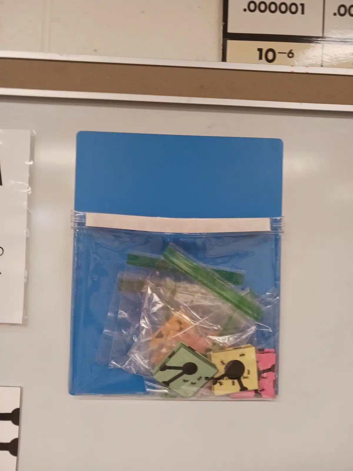 magnetic pouch from Charles Leonard hanging on dry erase board with ant farm puzzle pieces inside 