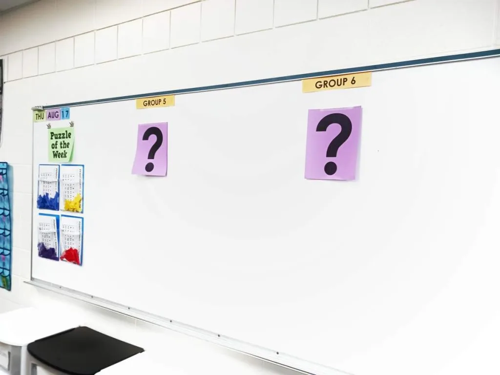 question mark posters hanging on dry erase board in high school math classroom 