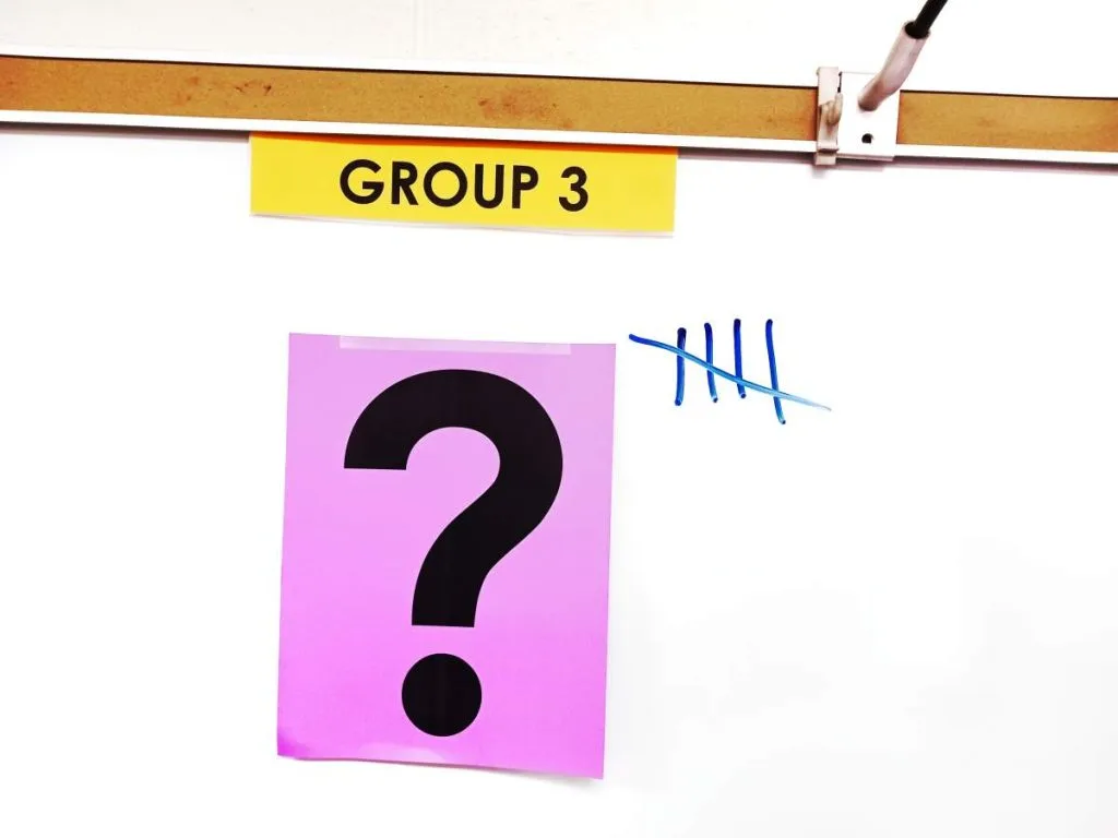 close-up of question mark poster hanging on dry erase board in math classroom with five tally marks next to poster 