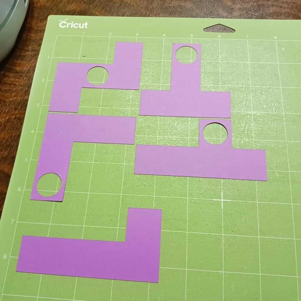 page of pentomino pieces with holes in them on cricut cutting mat. 