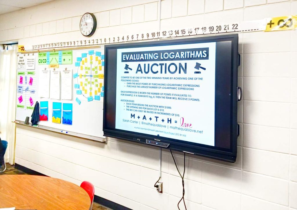 evaluating logarithms auction instructions displayed on promethean board in high school math classroom 