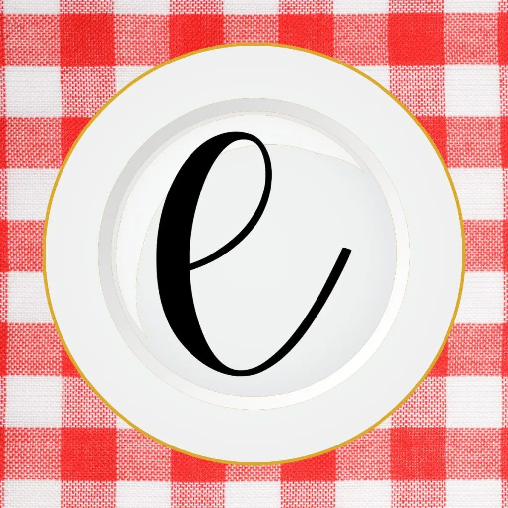 letter e on top of white plate on checkered tablecloth. 