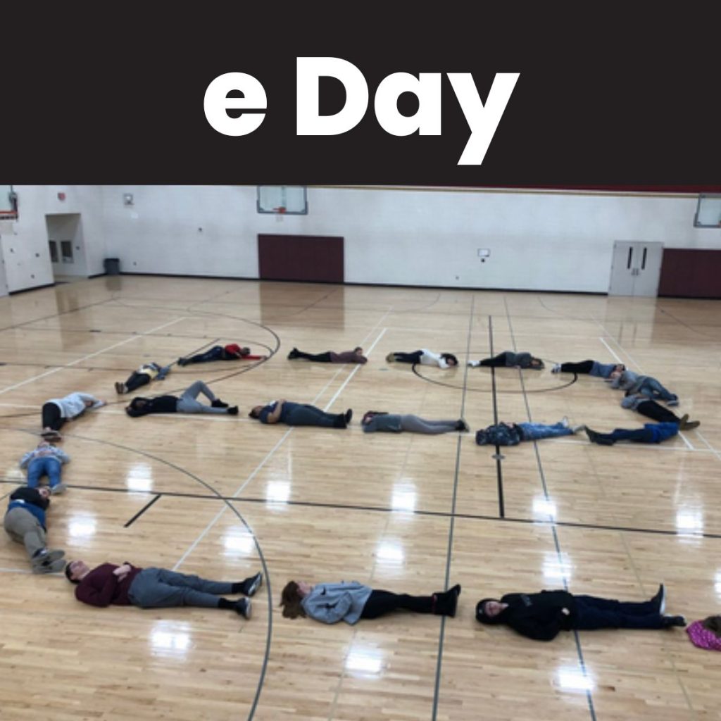 students laying on floor of gym in shape of e for "e day". 