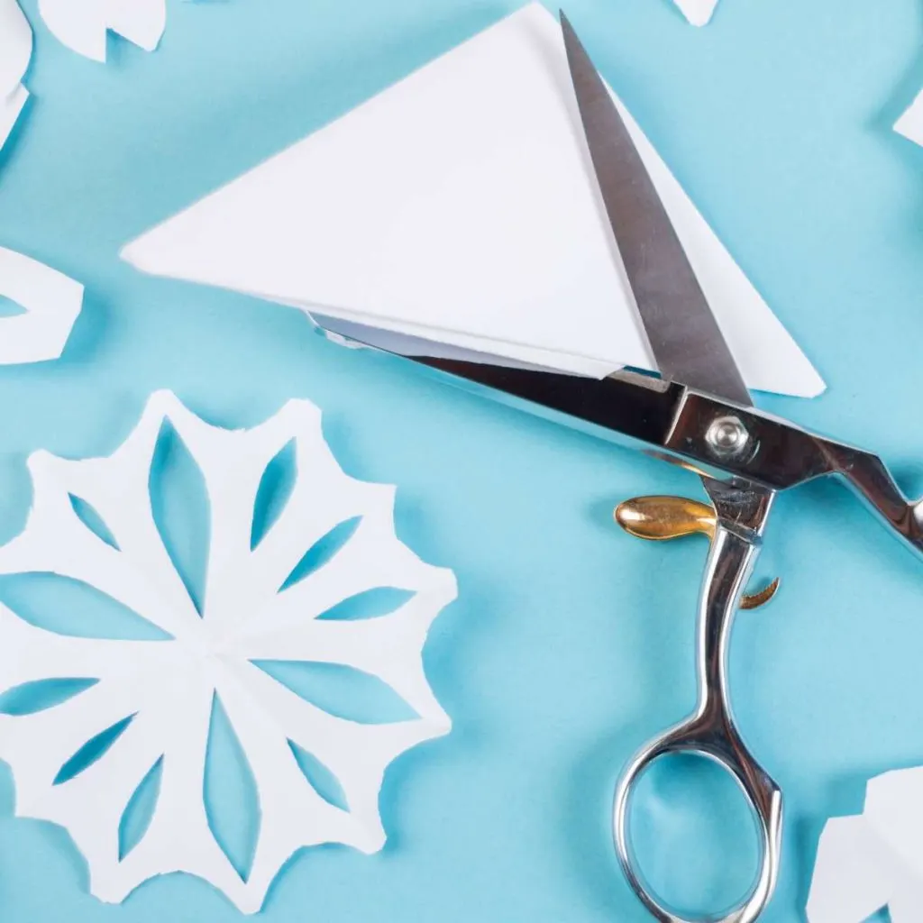 scissors cutting paper snowflake. 