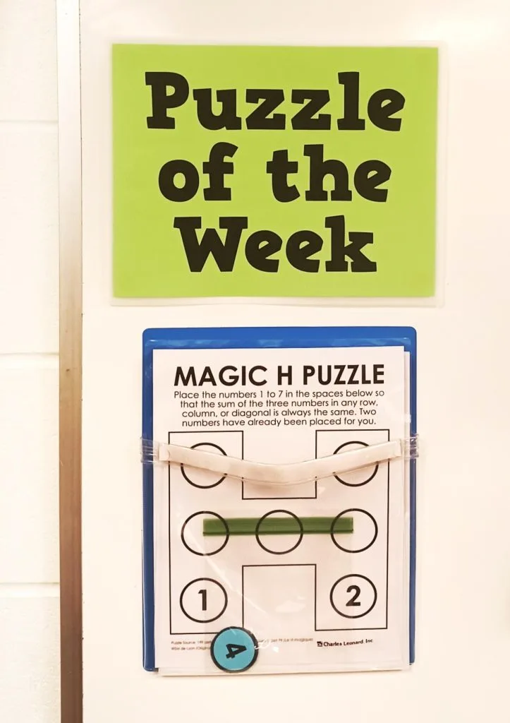 Magic H Puzzle in dry erase pocket under sign which reads "Puzzle of the Week" 
