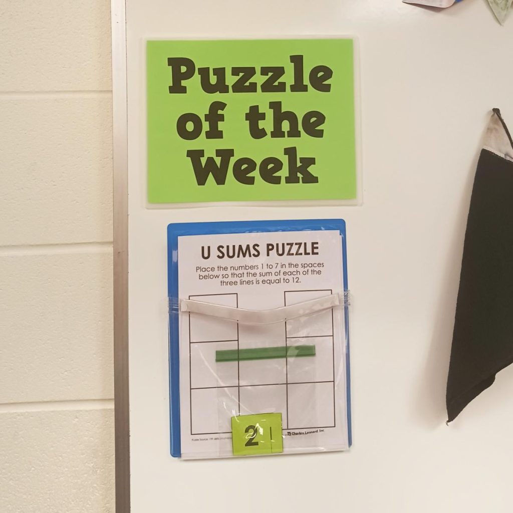 u sums puzzle hanging under sign reading "puzzle of the week" 