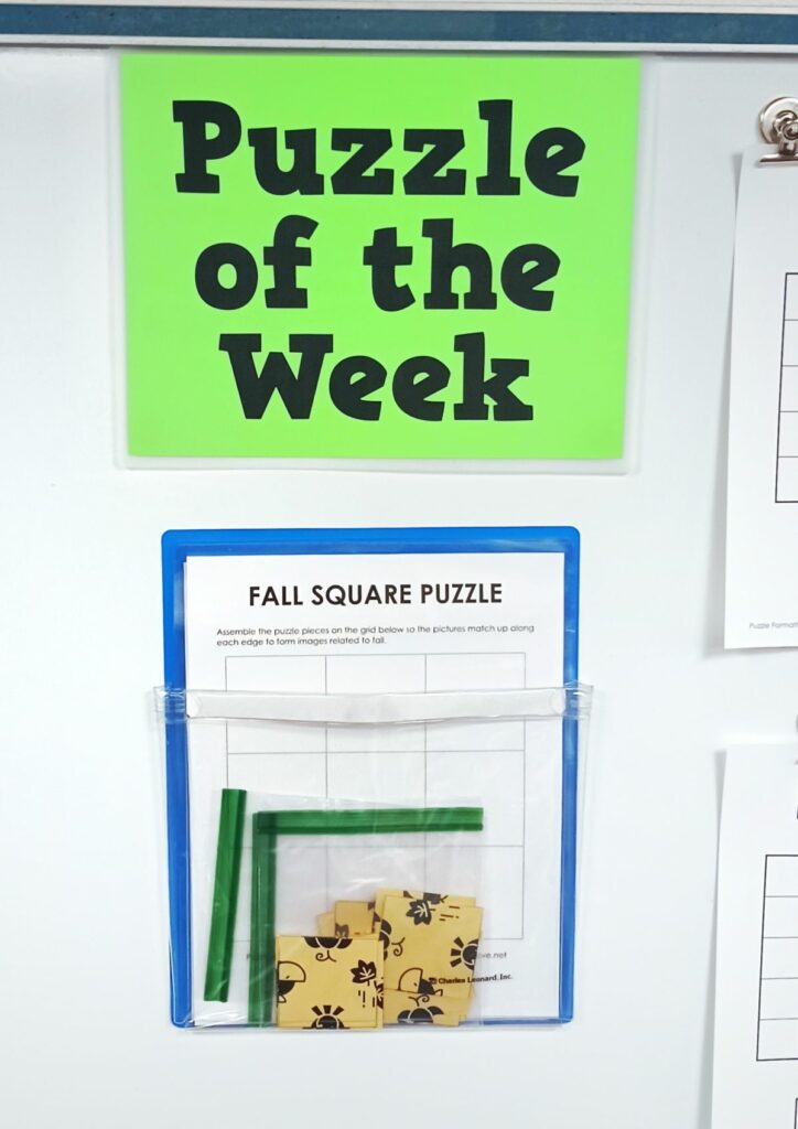 square fall logic puzzle hanging in magnetic pocket on dry erase board under sign reading "puzzle of the week" 