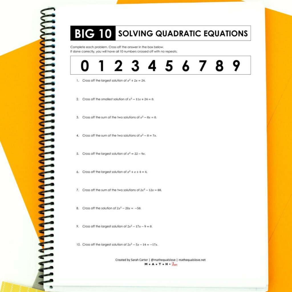 solving quadratic equations by factoring worksheet in notebook with orange paper in background. 