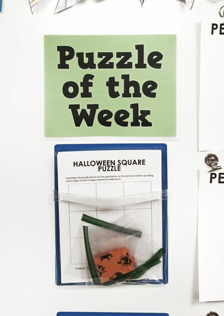 halloween square edge matching puzzle hanging in magnetic pocket under sign reading "puzzle of the week." 