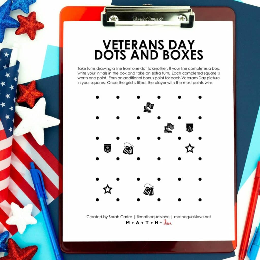 Veterans Day Dots and Boxes Game on clipboard next to patriotic decorations. 